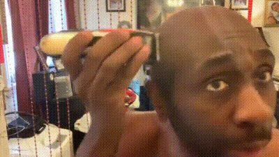 a man with a shaved head is looking at himself in the mirror