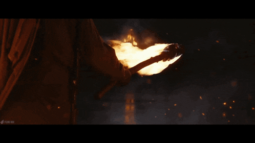 a man holding a torch in front of a burning mountain