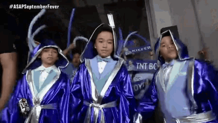 a group of young boys are dressed in blue robes with a sign that says tnt bc