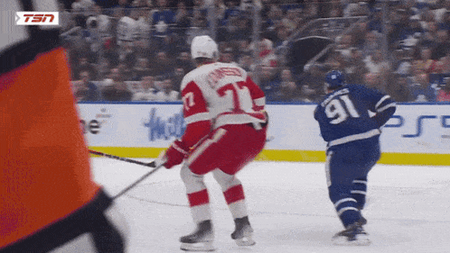 a hockey player with the number 91 on his jersey stands on the ice