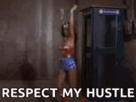 a woman in a wonder woman costume is dancing in front of a phone booth that says respect my hustle ..
