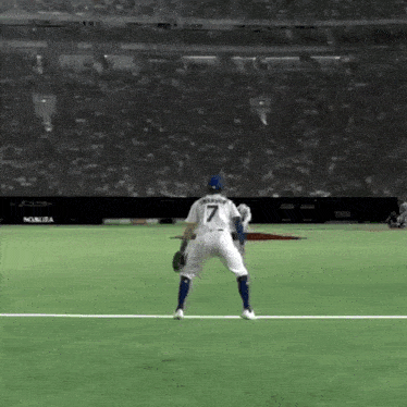 a baseball player with the number 7 on his back is standing on the field .