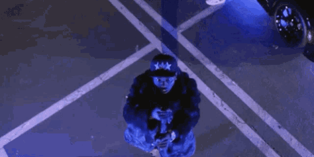 a man wearing a hat with three stars on it is kneeling down in a parking lot