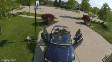 a blue convertible car is parked in a driveway with the doors open