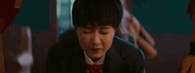 a young woman in a suit and red tie is looking up at something .