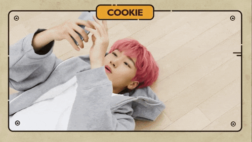 a person with pink hair is laying on the floor with a cookie sign above them