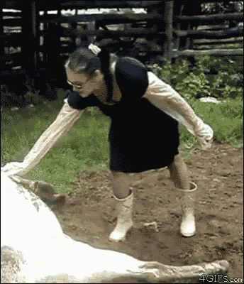 a woman in a black dress and white boots is standing next to a horse .