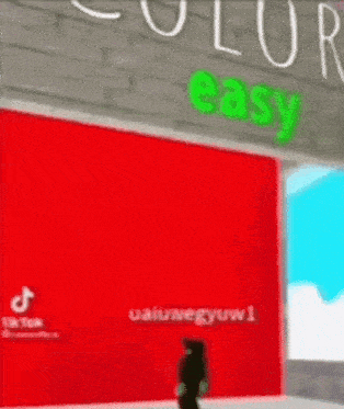 a person is standing in front of a red wall with a sign that says `` easy '' .