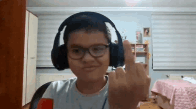 a young boy wearing headphones is giving the middle finger