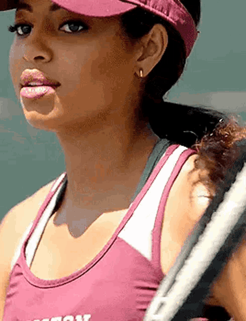 a close up of a woman wearing a visor and holding a tennis racquet .