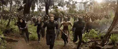 a group of avengers are running through a forest in a movie .