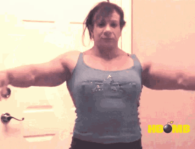 a woman in a blue tank top is standing in front of a door with the word hbomb on the bottom