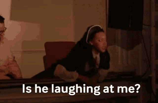 a woman is laughing at a man who is sitting behind her