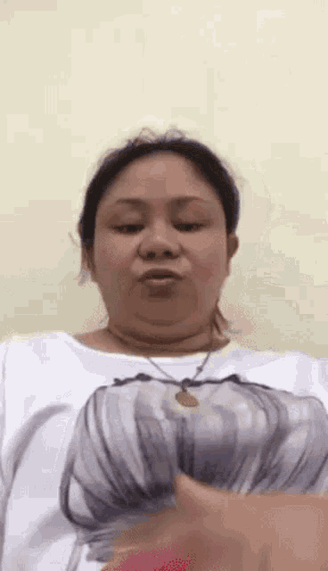 a woman is making a funny face while wearing a white shirt with a picture of a butterfly on it .
