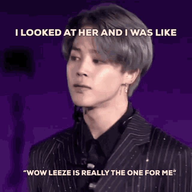 a man in a suit and tie is standing in front of a purple background and looking at a woman .