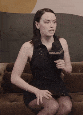a woman sitting on a couch holding a microphone with the word deadline on it