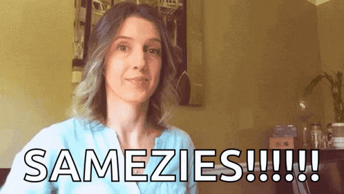 a woman in a blue shirt is standing in front of a wall that says samezies !!!
