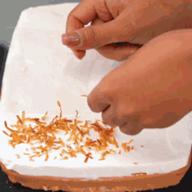 a person is adding coconut to a white cake