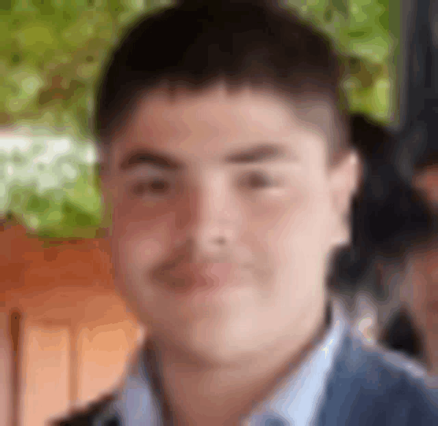 a young man in a blue jacket and white shirt is smiling for the camera .