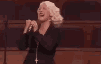 a woman is laughing while holding a microphone in a theater .