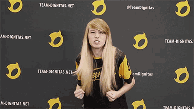 a woman stands in front of a team-dignitas.net sign