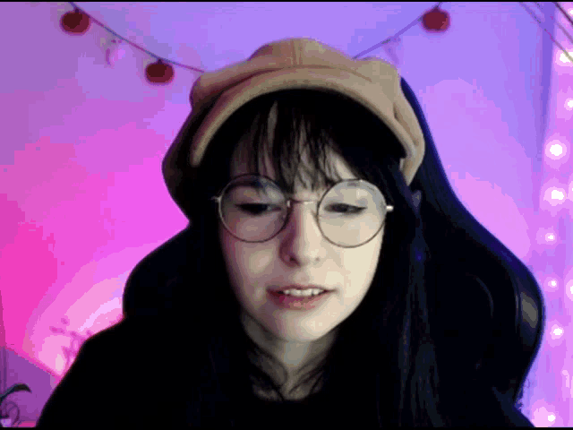 a girl wearing glasses and a hat looks at the camera