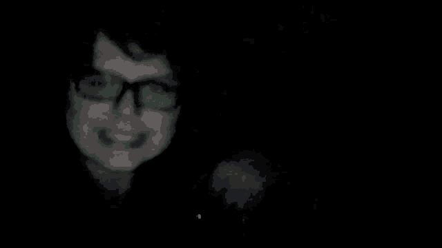 a black and white photo of a person 's face in a dark room .
