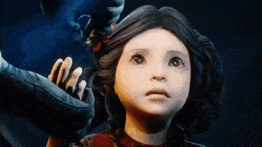 a little girl in a red dress is looking up at a person 's hand .