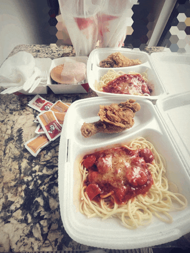 two styrofoam containers of spaghetti and chicken on a counter top