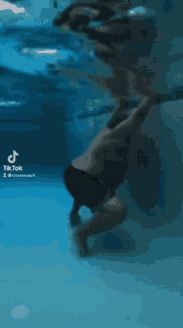 a man is swimming underwater in a pool with tiktok written on the bottom of the screen