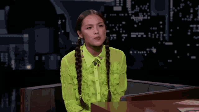 a woman in a neon green shirt is sitting in front of a piano