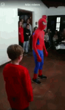 a man in a spiderman costume is standing next to a boy in a red shirt