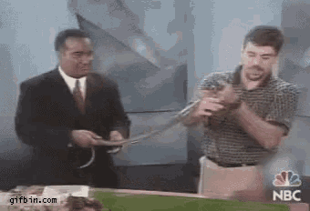 a man in a suit is holding a snake in front of a nbc sign