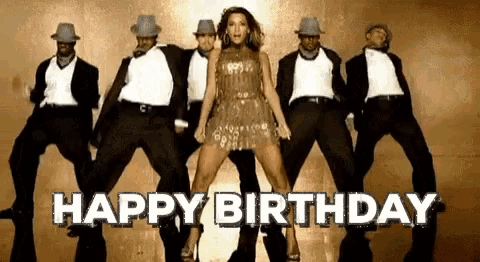 a woman is dancing in front of a group of men with the words `` happy birthday '' written above her .