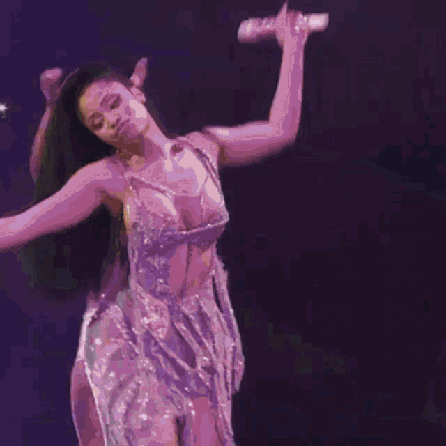 a woman in a purple dress is singing into a microphone on a stage