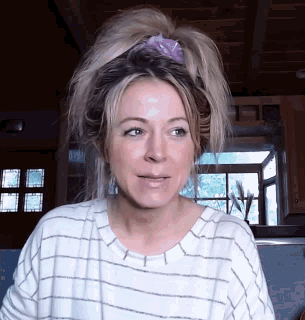 a woman wearing a striped shirt and a ponytail looks at the camera