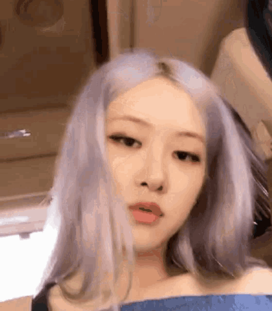 a close up of a woman 's face with gray hair and a blue shirt .