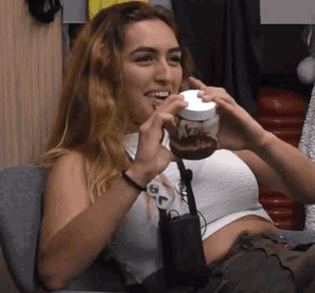 a woman is sitting in a chair holding a jar of chocolate spread .