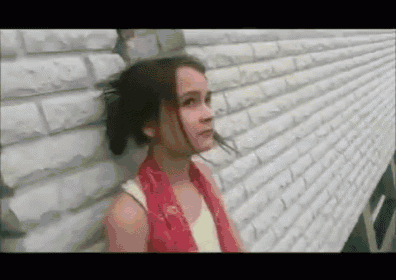 a girl is leaning against a white brick wall .