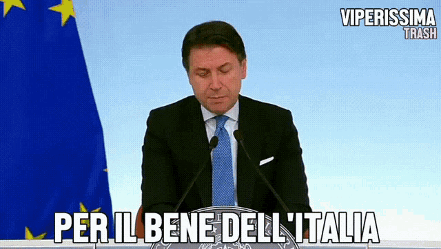 a man in a suit and tie is giving a speech with the words per il bene dell ' italia written below him