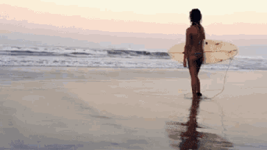 a woman in a bikini is carrying a surfboard on a beach