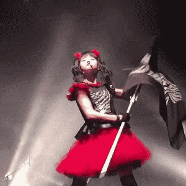 a girl in a red dress is holding a black flag