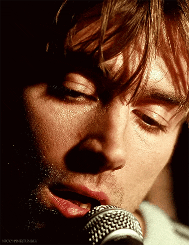 a close up of a man singing into a microphone with the words nicky-pinkitumblr below him