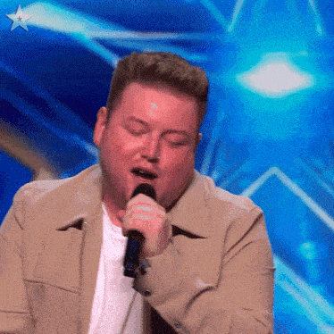 a man singing into a microphone in front of a blue star