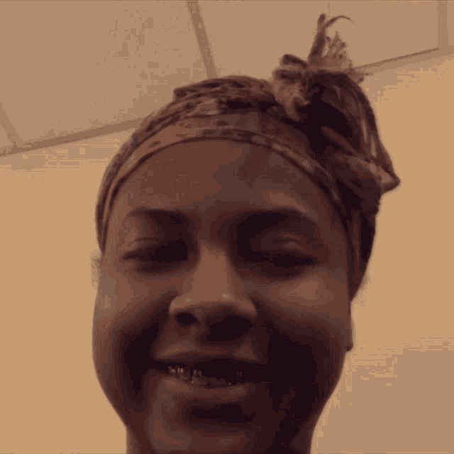 a woman wearing a head scarf and braces smiles