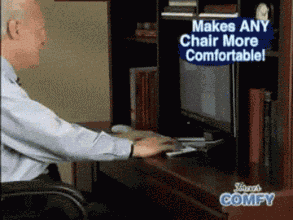 a man sits at a desk in front of a computer and a sign that says " makes any chair more comfortable "