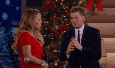 a man and a woman standing in front of a christmas tree