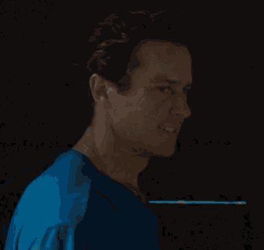 a man in a blue shirt is smiling and looking at the camera .