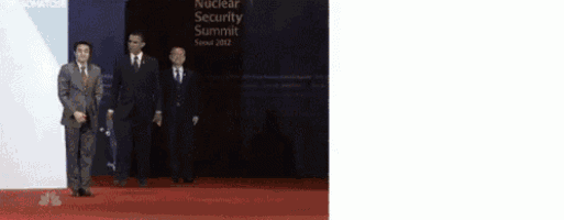 a group of men are standing in front of a sign that says nuclear security summit