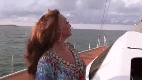 a woman is standing on the deck of a sailboat in the ocean .